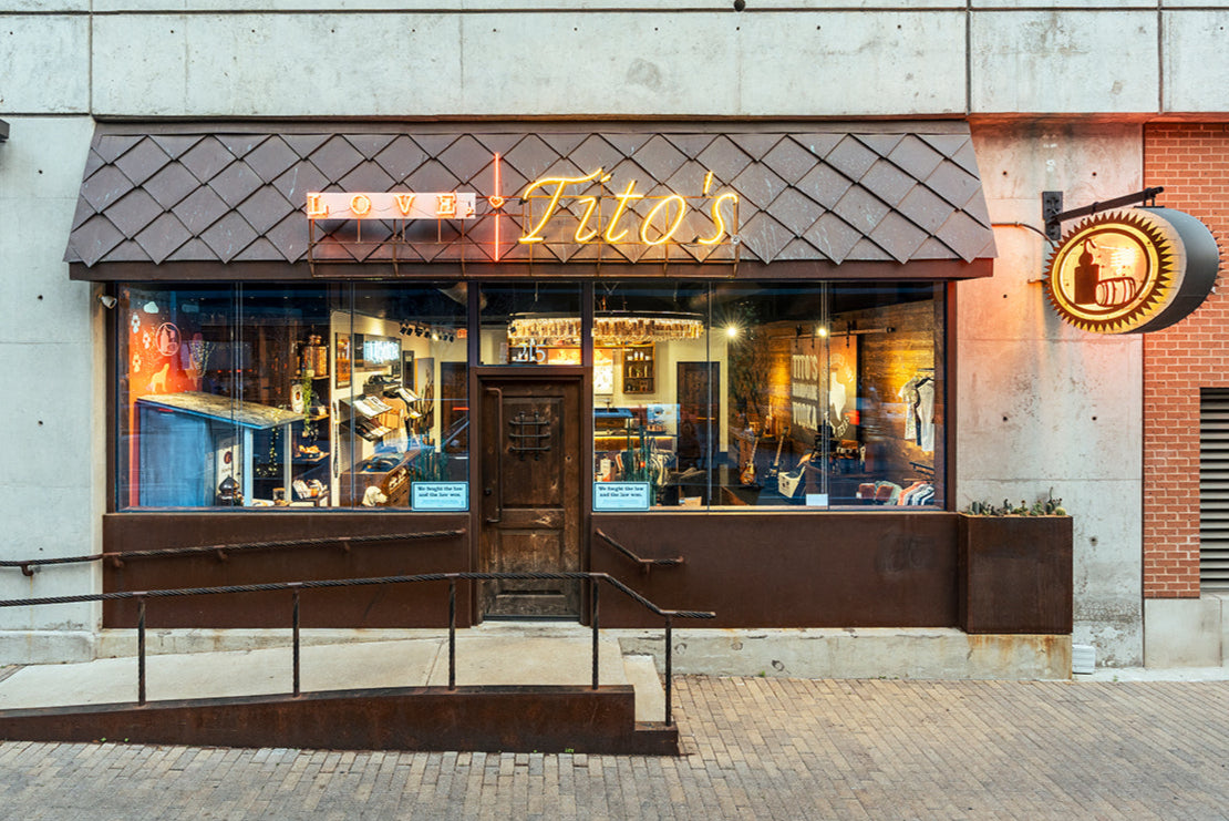 exterior view of the Love, Tito's store with the Love, Tito's logo in neon, large glass windows showcasing merchandise inside