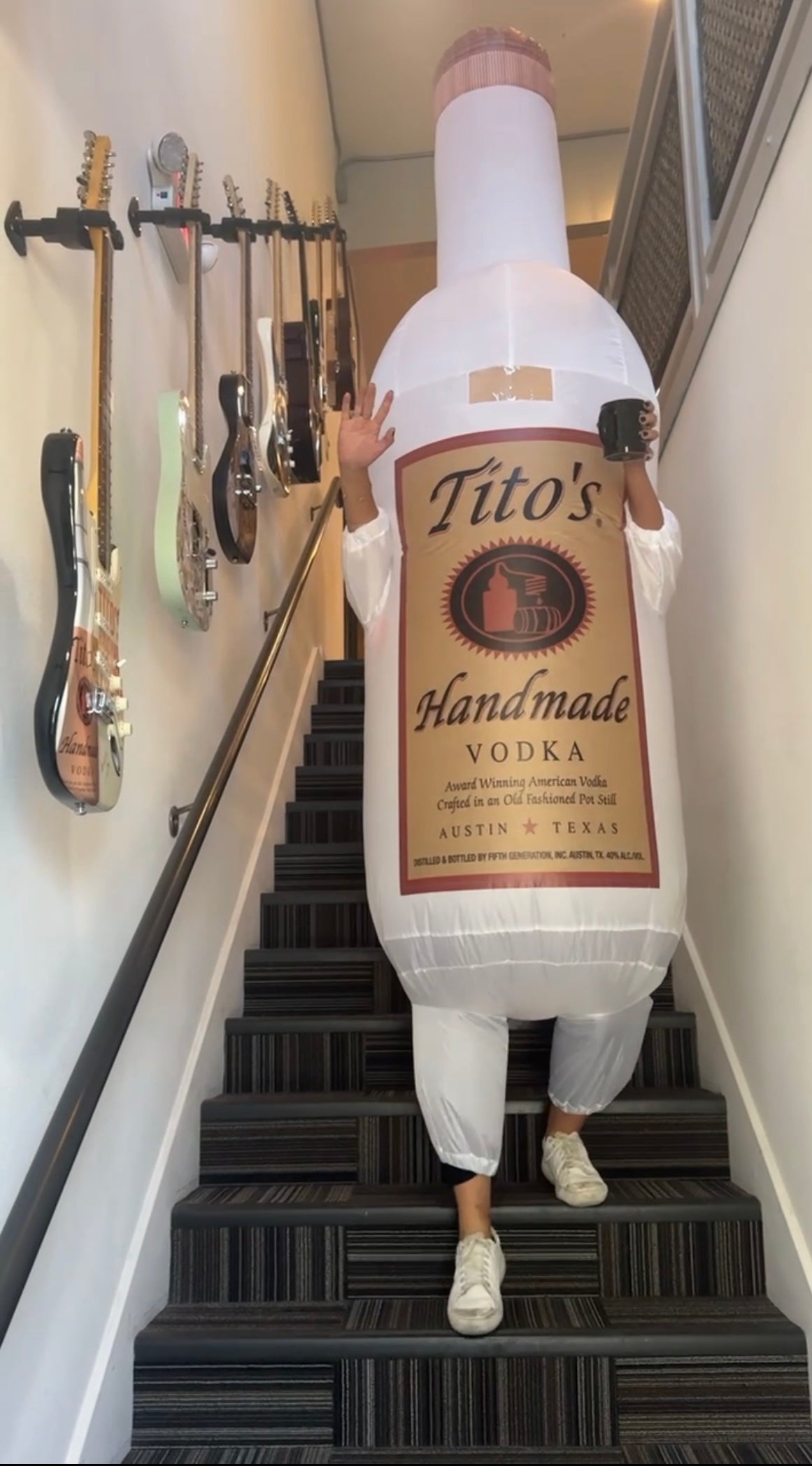 Person wearing Tito's inflatable bottle costume walking down stairs