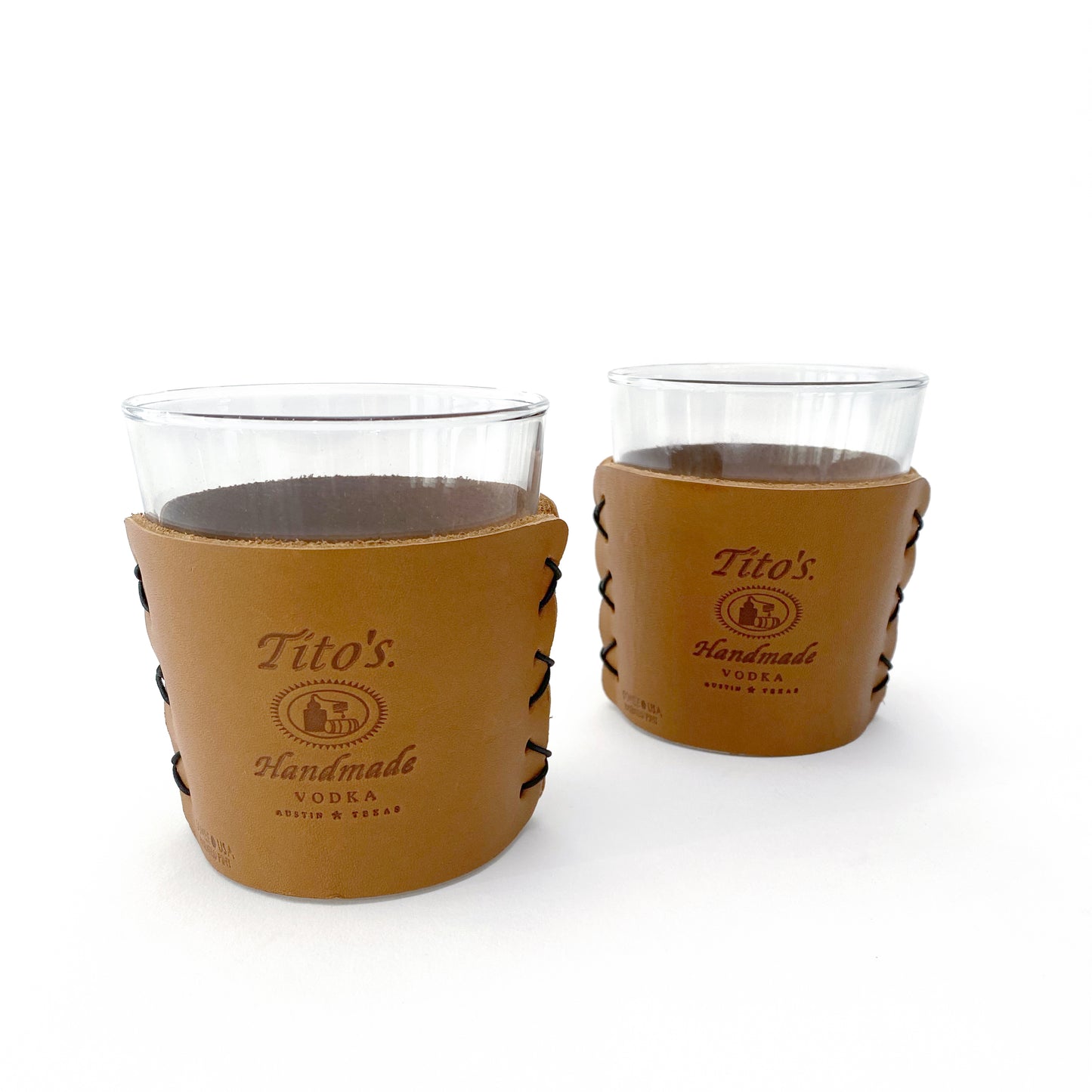Packaged set of highball cocktail glasses in leather sleeves branded with Tito's Handmade Vodka logo