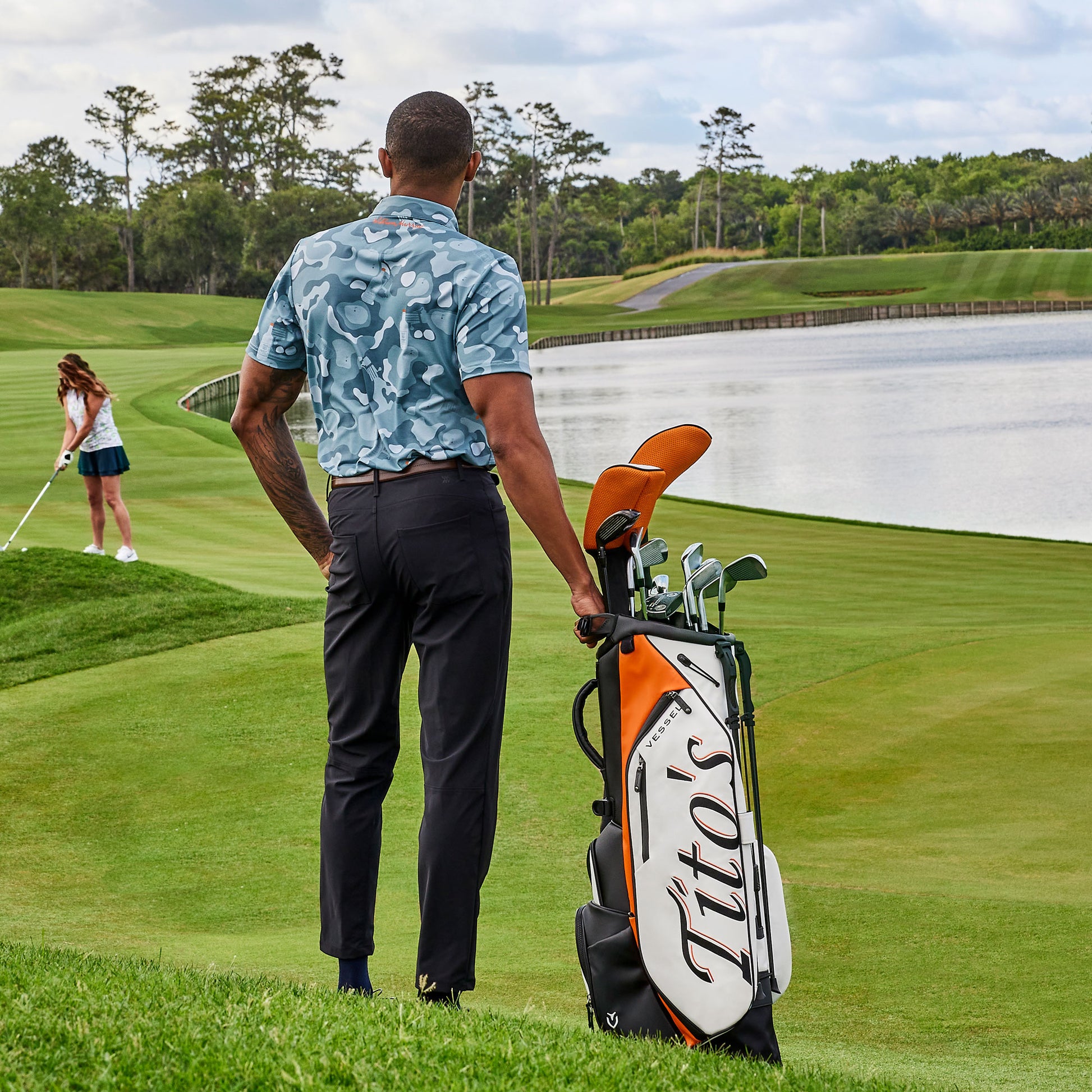 Man on golf course with Tito's X VESSEL Golf Bag wearing blue Tito's X William Murray Bottle in Disguise Golf Polo
