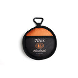 Closed view of black, orange, and white collapsible dog bowl with Tito's Handmade Vodka logo and dog leash carabiner