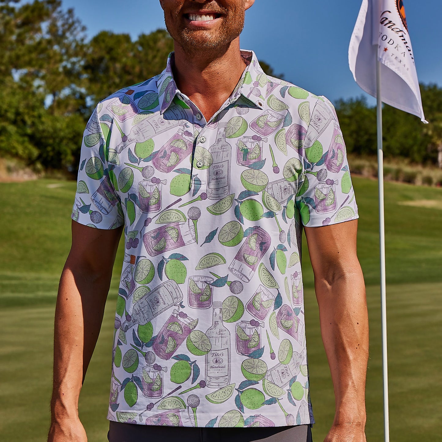 Man on golf course wearing white Tito's X William Murray Transfusion Men's Golf Polo