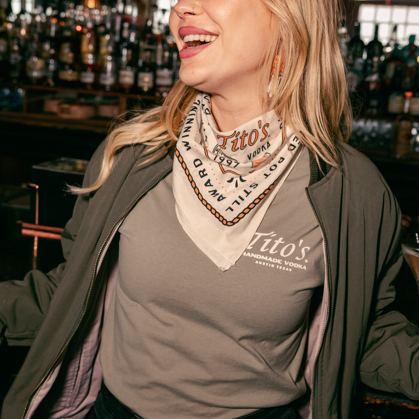 person wearing Tito's '97 bandana around their neck in a bar
