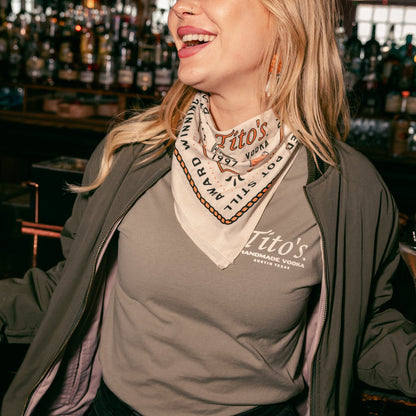 person wearing Tito's '97 bandana around their neck in a bar