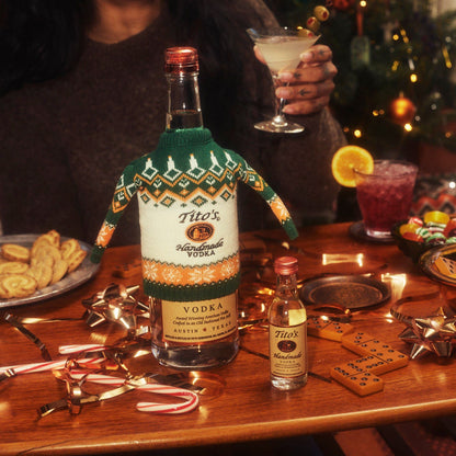 Bottle of Tito's Handmade Vodka with a Ugly Bottle Sweater on a table full of games and cocktails 
