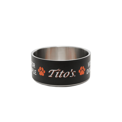 A black and stainless steel dog bowl featuring the orange and white 'Tito's' logo, Vodka for Dog People words, and paw prints on the exterior, set against a plain white background.