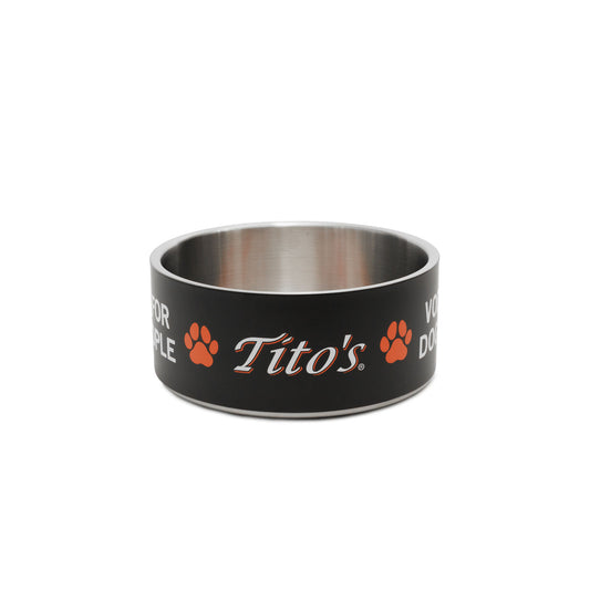 A black and stainless steel dog bowl featuring the orange and white 'Tito's' logo, Vodka for Dog People words, and paw prints on the exterior, set against a plain white background.