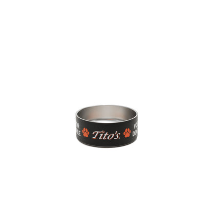 A black and stainless steel dog bowl featuring the orange and white 'Tito's' logo, Vodka for Dog People words, and paw prints on the exterior, set against a plain white background.