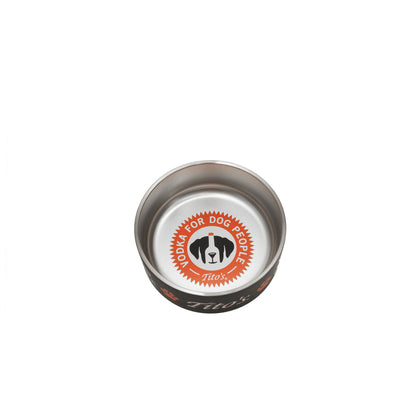 A stainless steel dog bowl with a black exterior, featuring a circular orange, white, and black logo on the inside that reads 'VODKA FOR DOG PEOPLE' and 'Tito's' . The brand name 'Tito's' is also visible on the outside of the bowl.