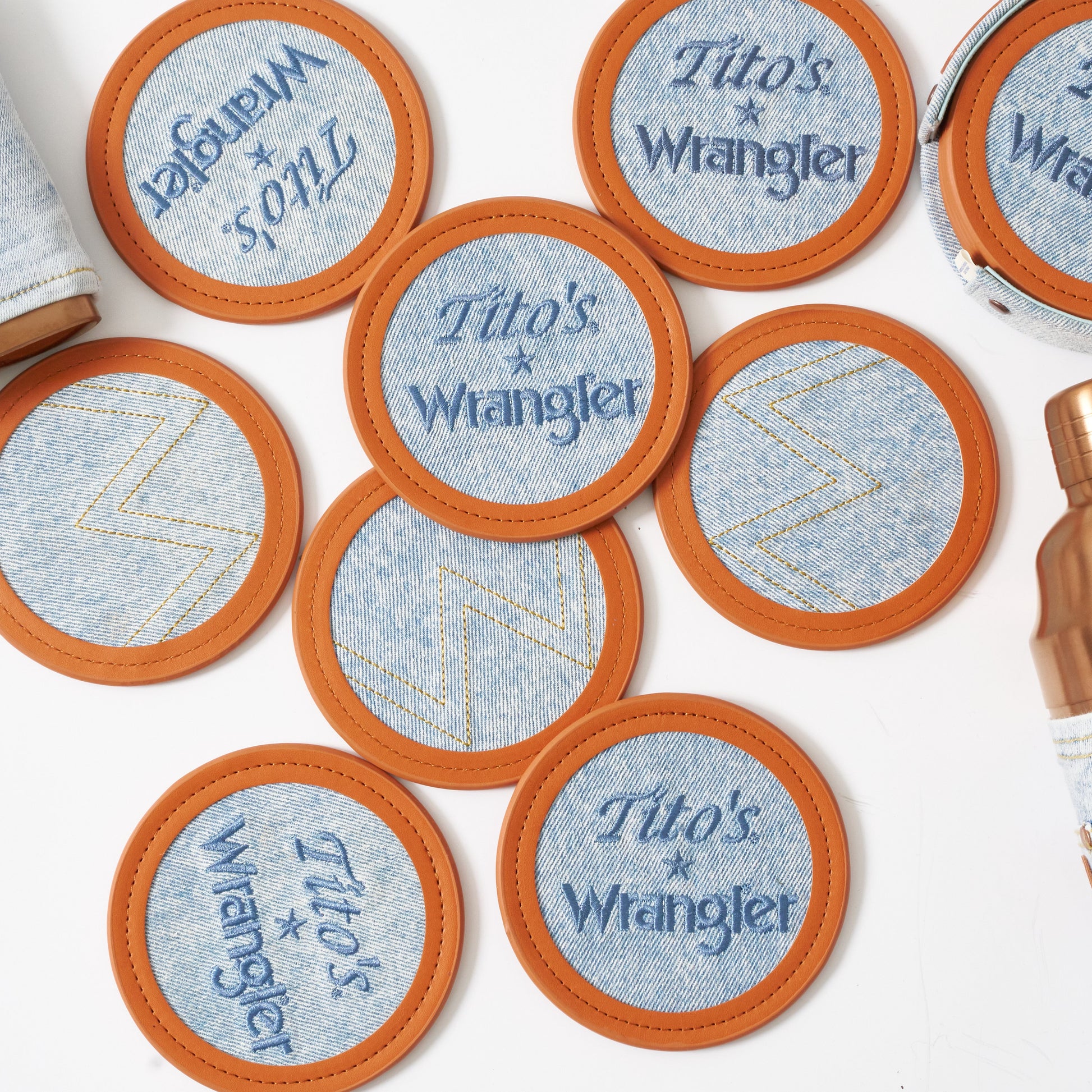 Multiple sets of Wrangler coasters laid out, some face up showing the embroidered Tito's and Wrangler logos and other with the sticked "W' from wrangler pockets