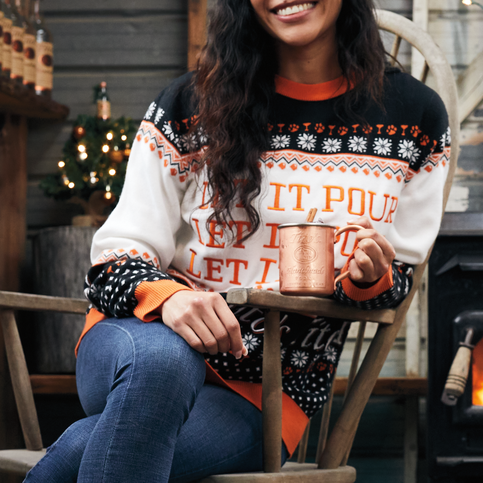 Woman wearing Tito's Kinda Ugly Sweater holding a Tito's Copper Mug