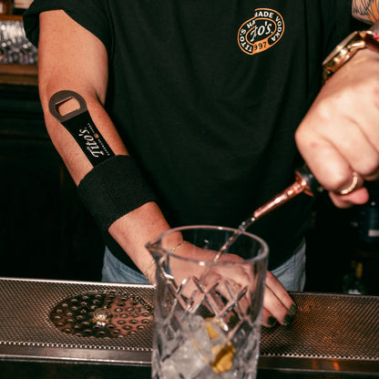 Person preparing a drink at a bar with a Tito's Bar Key on their arm