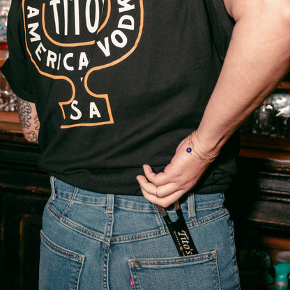 Person wearing a Tito's Martini Tee pulling a Tito's bar Key out of their back pocket