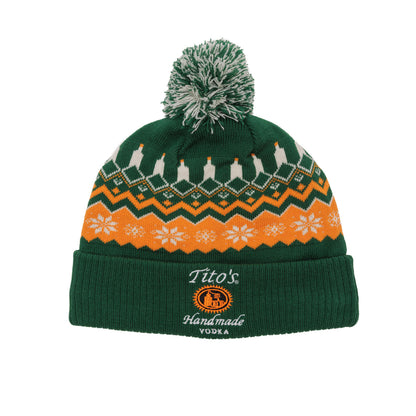Green knit beanie with pom poms with orange and white festive patterns and Tito's Handmade Vodka logo embroidered on the cuff. 