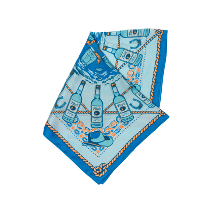 Blue silk scarf with pattern of Tito's Handmade Vodka bottles, cowboy hats, cocktails, and rope folded into a triangle