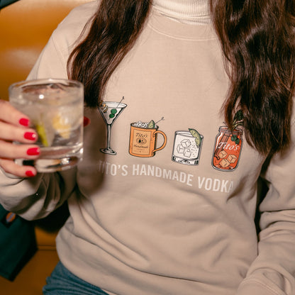 front view of a person wearing a Tito's Classic Cocktail crewneck holding a Tito's Soda Lime cocktail 