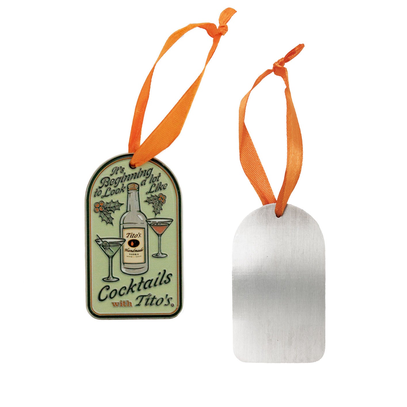 2 ornaments_ one showing the front of Green, enamel, oval-shaped ornament that says "It's beginning to look a lot like cocktails with Tito's", a bottle of Tito's and a dirty Tito's martini and Tito's Espresso martini with an orange ribbon and the other showing the back of the ornament is metal