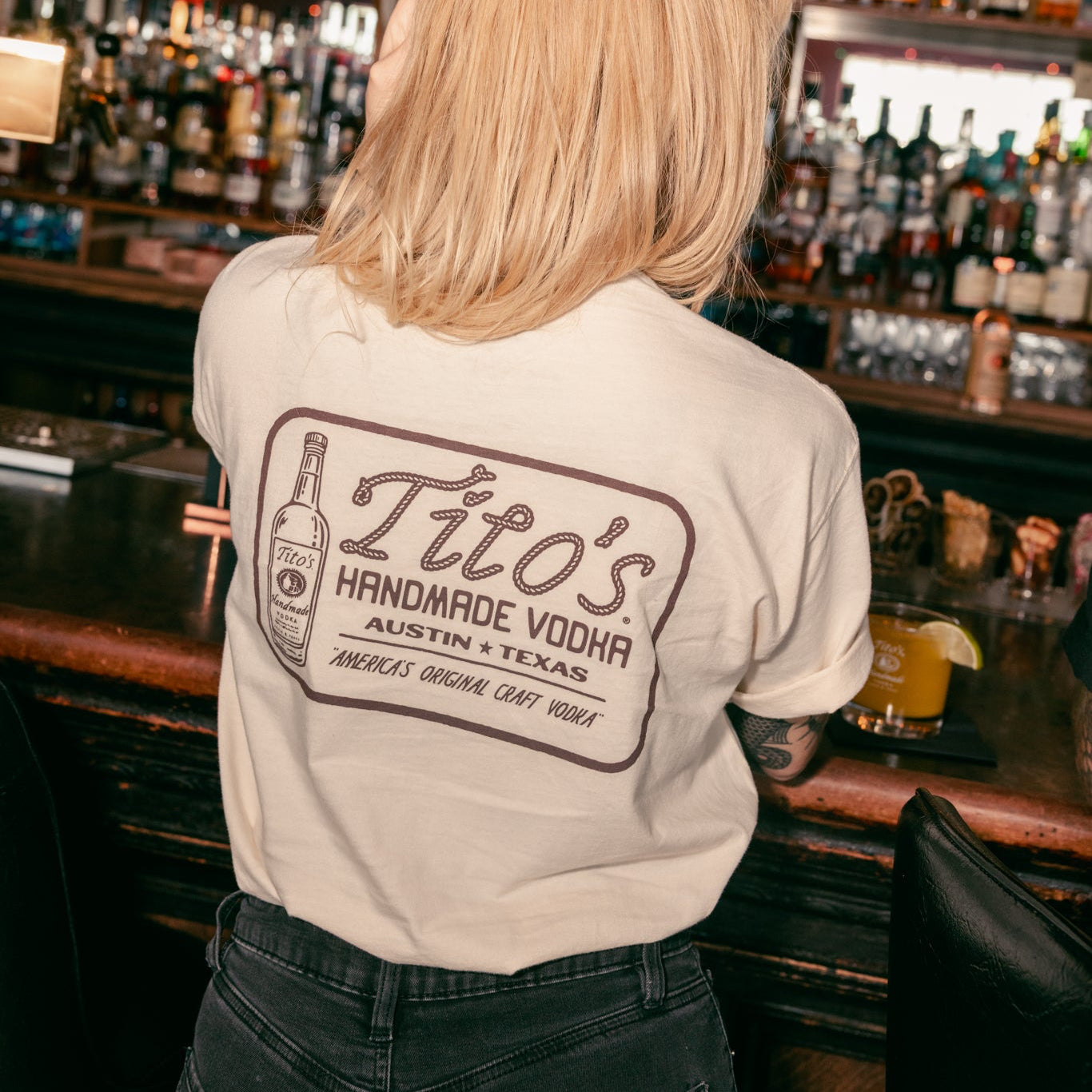Person wearing a Tito's Rodeo Tee at a bar 