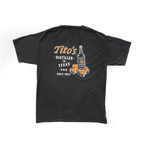 Back of slate grey short sleeve shirt with Tito's bottle on top of orange Texas outline, next to Tito's wordmark and "Distilled in Texas since 1997" text