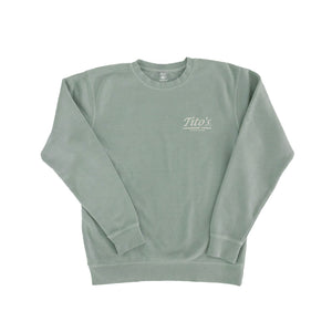 Front of sage green crewneck pullover with Tito's Handmade Vodka and Austin, Texas badge