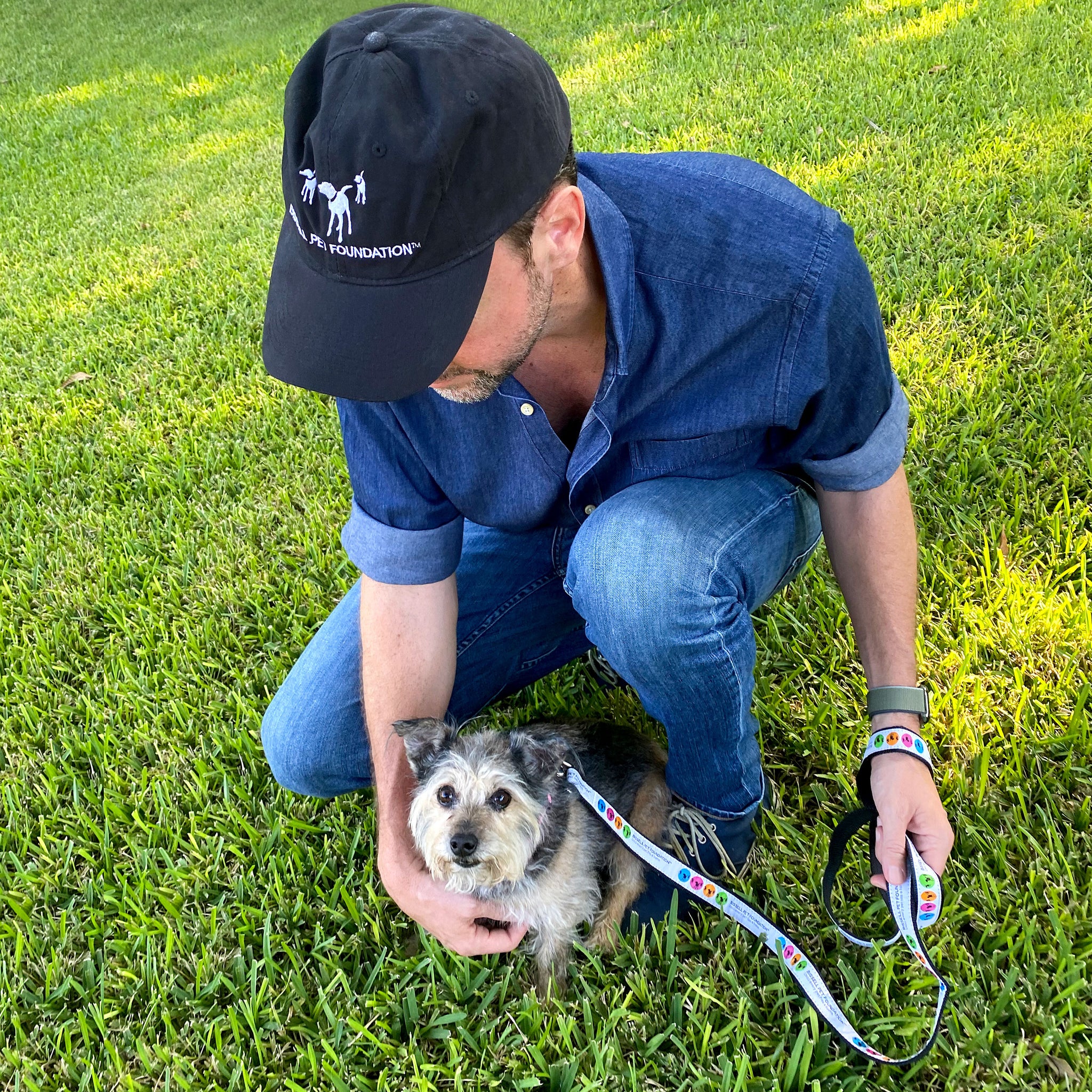 Man wearing BISSELL Pet Foundation Cap with dog wearing BISSELL Pet Foundation Dog Leash