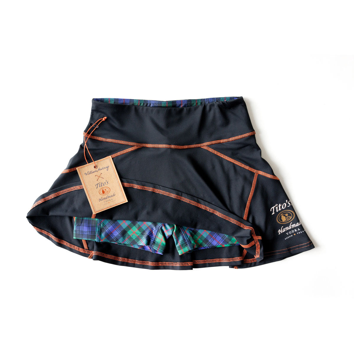 Front of black skort with orange stitching, green and purple plaid shorts, Tito’s Handmade Vodka logo
