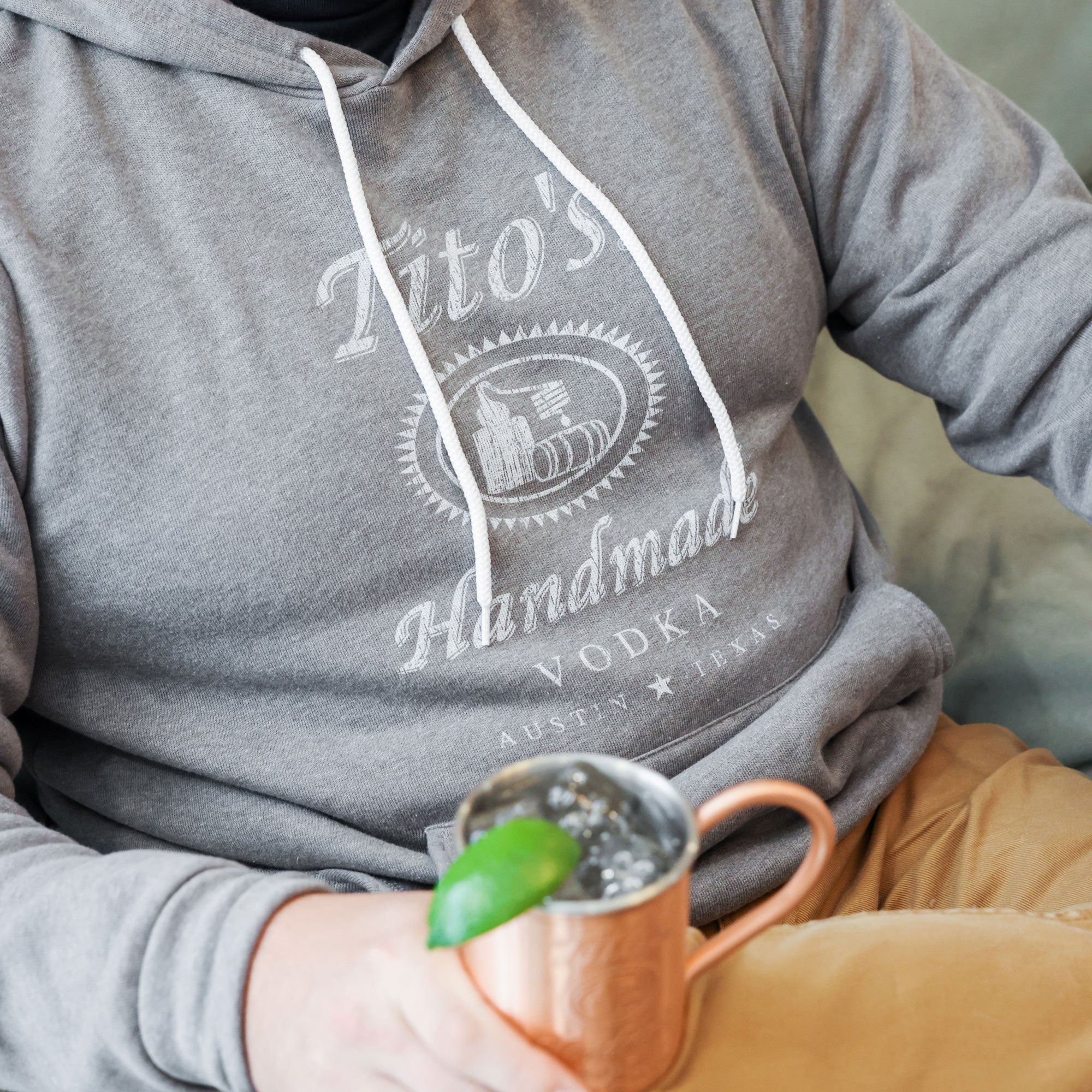 Man wearing Tito's Classic Gray Hoodie with a cocktail in a Tito's Copper Mug