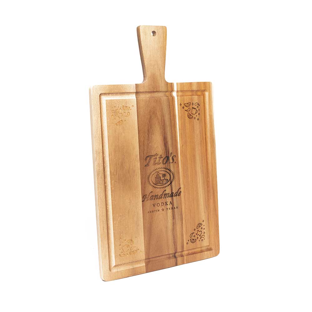 Wooden cutting board with groove around edges, Tito's Handmade Vodka logo in the center and garnish designs on the corners