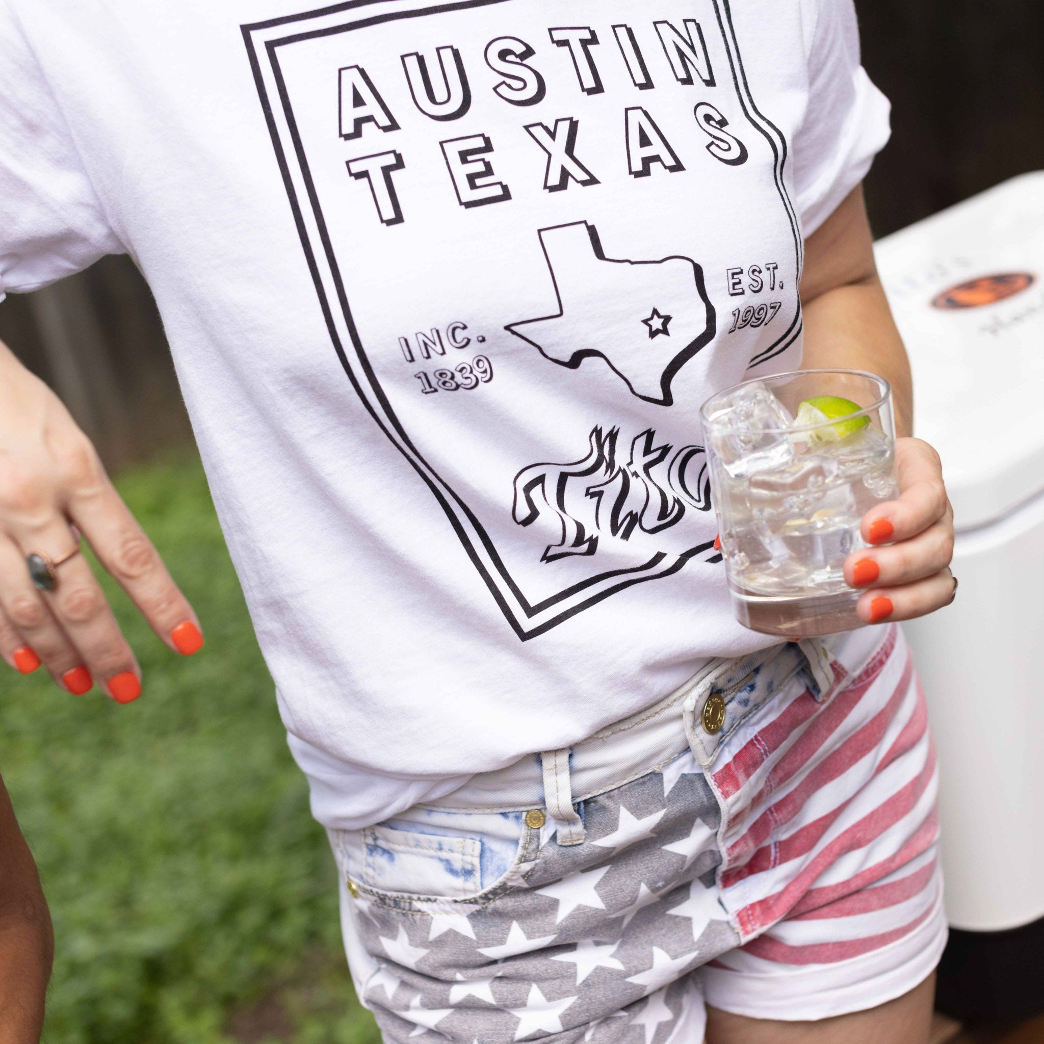 Girl wearing Tito's Hometown Hero Tee and holding a cocktail