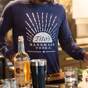 Man wearing navy long-sleeved t-shirt with Tito's Handmade Vodka mark and sunrise design