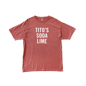 Rust colored t-shirt withWashed red t-shirt Tito's Soda Lime white text on the front 