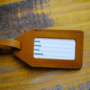 Back view of brown leather luggage tag with clear window for contact information