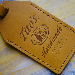 Detail view of brown leather luggage tag with Tito's Handmade Vodka logo