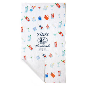 White towel with Tito's Handmade Vodka logo and assorted cocktail illustrations with bottom left corner folded over to show solid white back