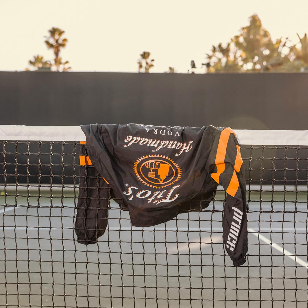 Black track jacket laying on top of tennis net